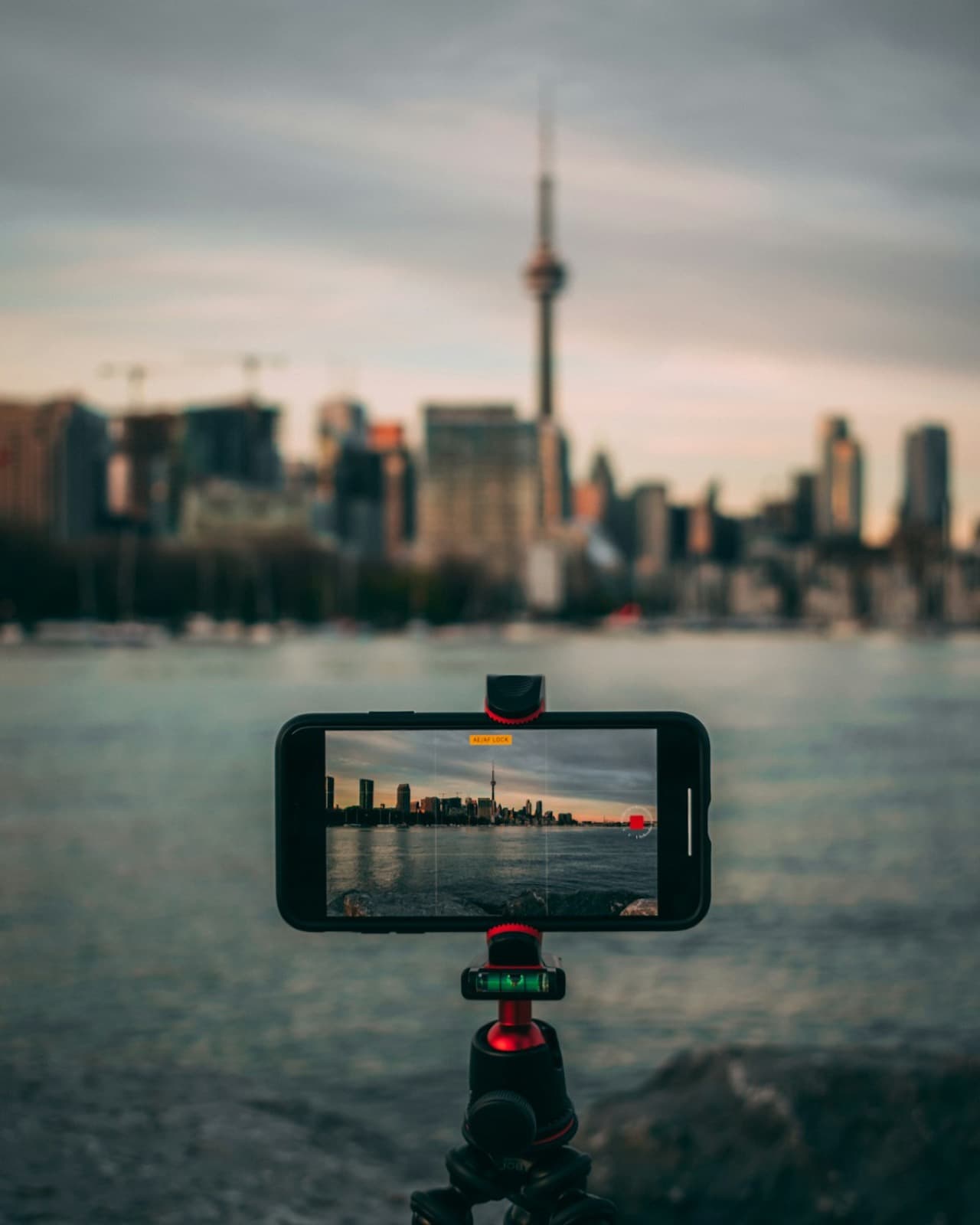Téléphone posé sur un trépied, en train de filmer une ville au bord de l’eau
